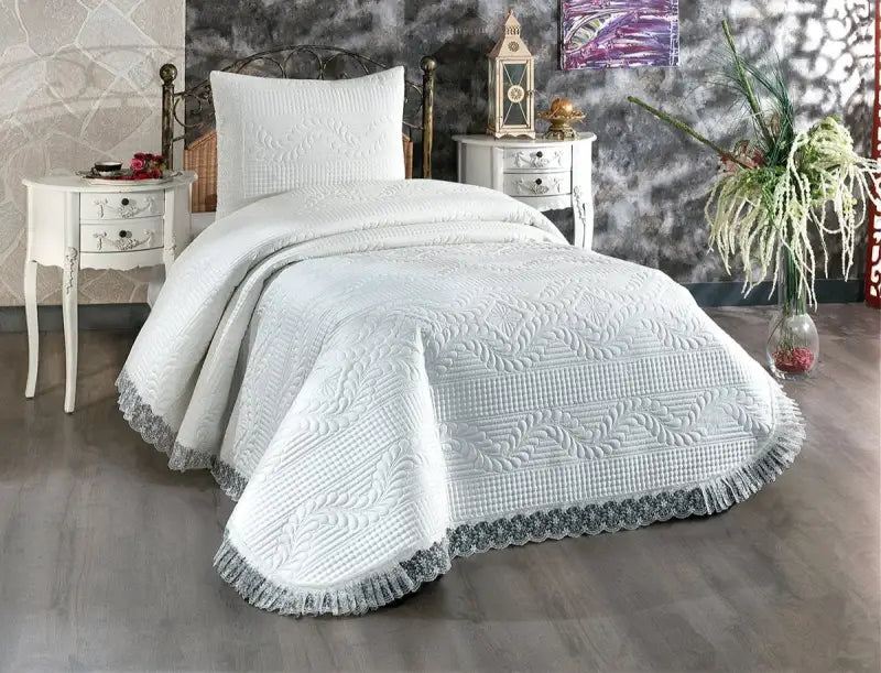 White quilted bedspread with ruffled edges and textured pattern.