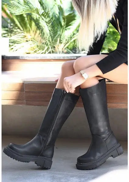 Black leather knee-high platform boots with chunky treaded soles.