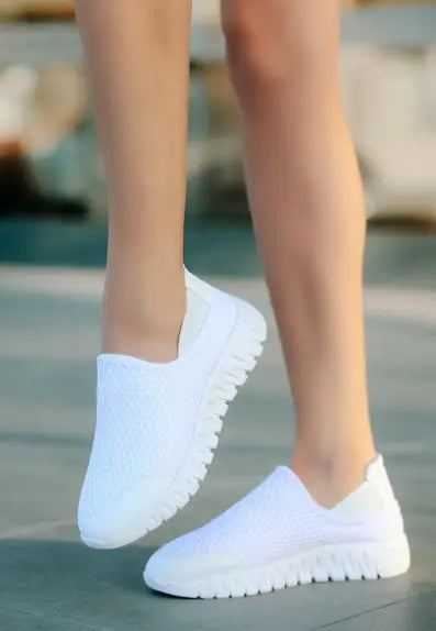 White slip-on sneakers with ridged platform soles.