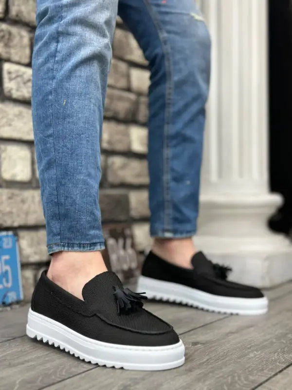 Black tassel loafers with white platform soles.