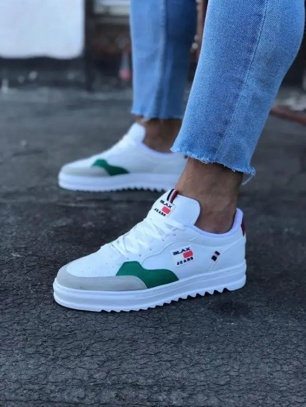 White athletic sneaker with green accents and red branding details.