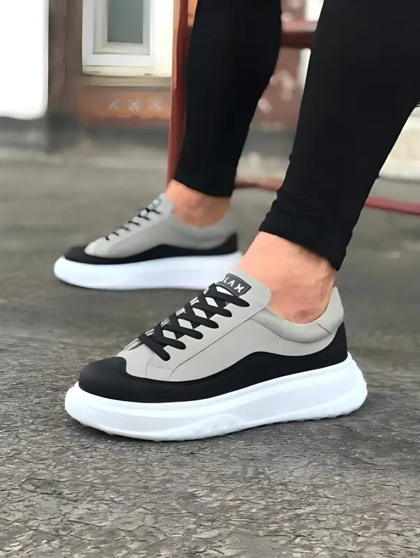 Two-tone sneakers with grey and black panels on a thick white platform sole.