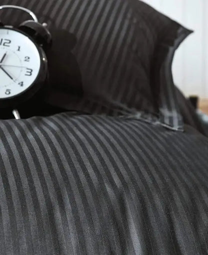 Black and gray striped bedding with an alarm clock on top.