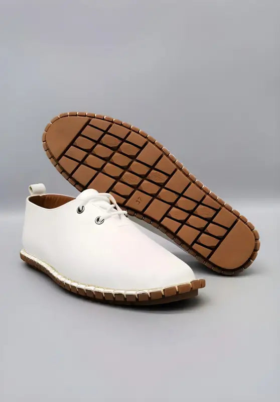 White leather lace-up shoe with a brown rubber grid-patterned sole.