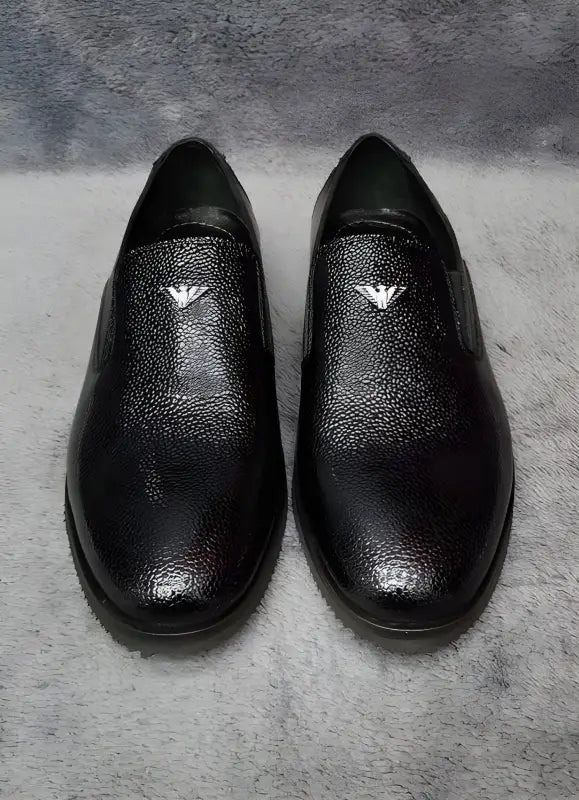 Pair of black leather slip-on dress shoes with eagle logos.