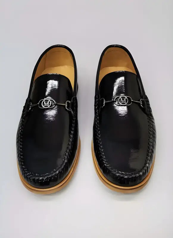 Black leather loafers with silver metal hardware and tan soles.