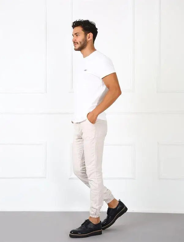 Someone wearing a white t-shirt, light-colored joggers, and black dress shoes in a casual pose.