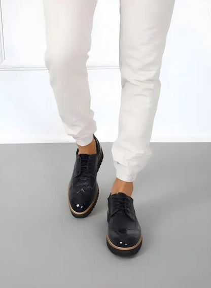 Black leather oxford shoes with metallic toe caps and chunky soles.