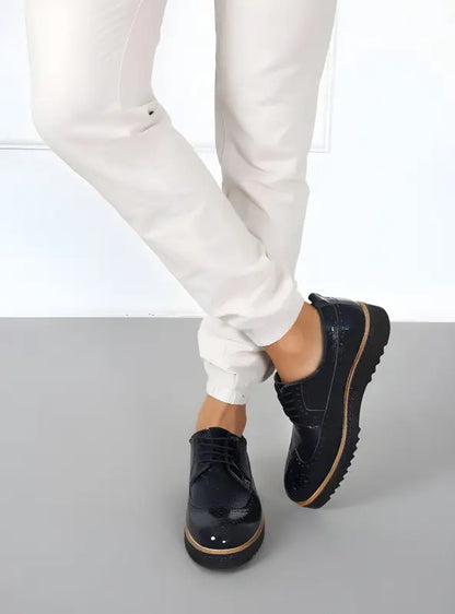 Black leather oxford shoes with contrast stitching and a platform sole.