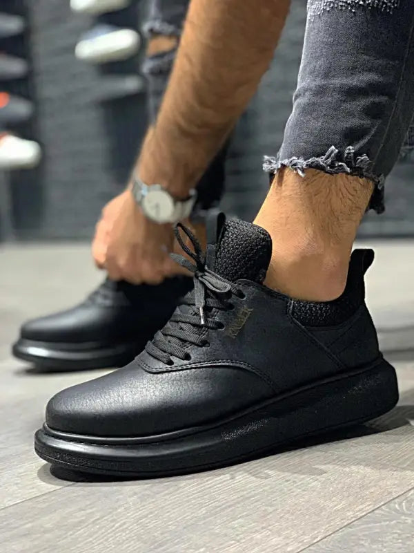 Black leather sneakers with thick soles and sock-like collar detail.