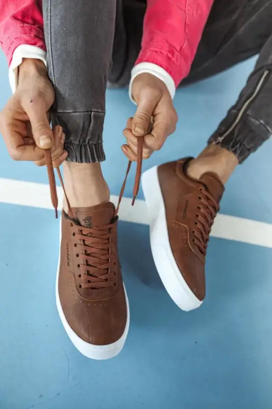 Brown lace-up sneakers with white soles.