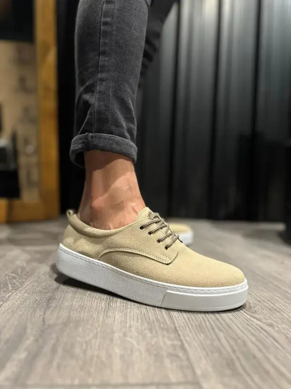 Beige suede sneaker with white platform sole and brown laces.