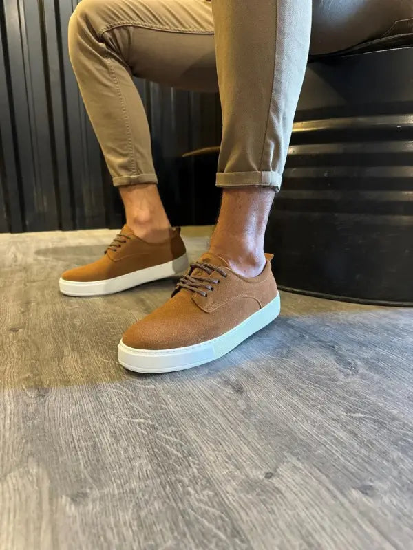 Brown leather sneakers with white soles and tan laces.