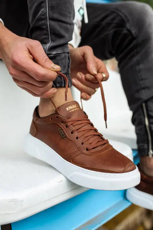 Brown leather sneaker with white platform sole and tan collar detail.