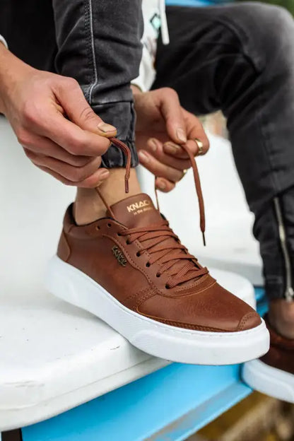 Brown leather sneaker with white platform sole and tan collar detail.