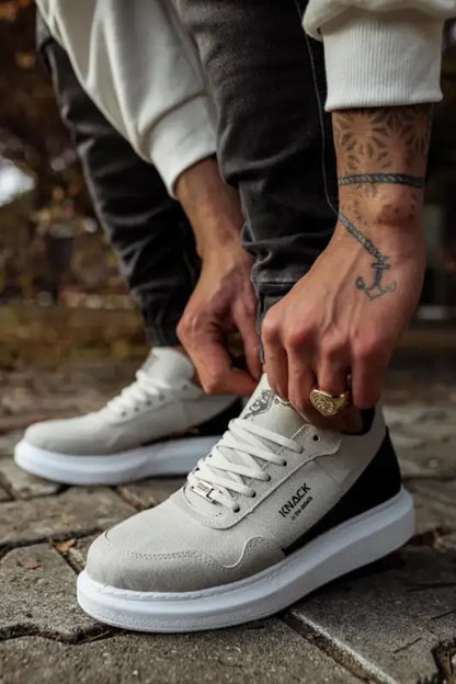 Grey and white sneaker with black accents being laced up.