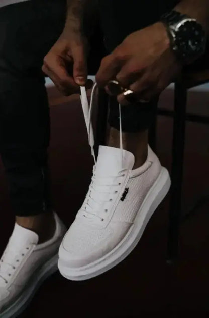 White leather sneaker with laces being tied.