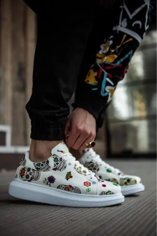 White sneakers decorated with colorful cartoon-style skull and floral patterns.