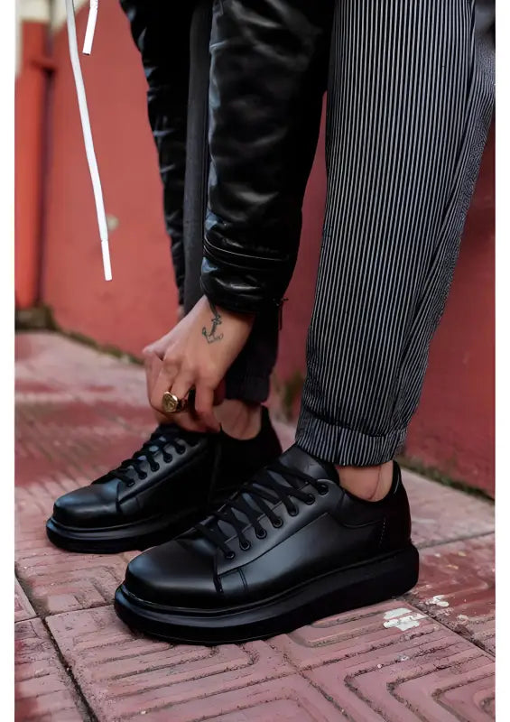 Black leather sneakers with thick soles and dark laces.