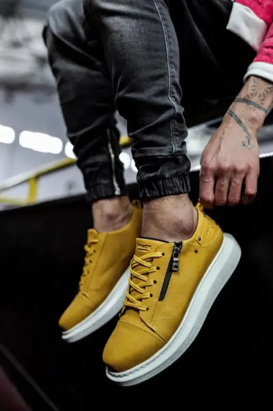 Yellow leather sneakers with white soles and yellow laces.