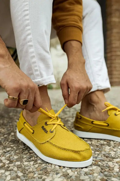 Yellow leather boat shoes with white soles and brown laces.