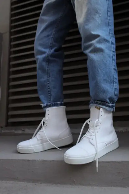 White high-top leather sneakers with laces paired with blue jeans.