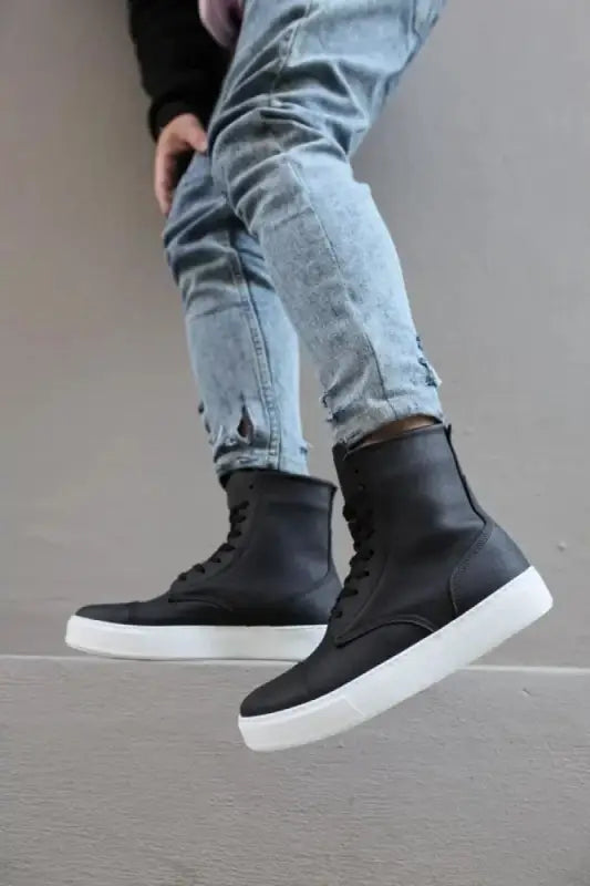 Black high-top sneakers with white soles worn with light blue jeans.