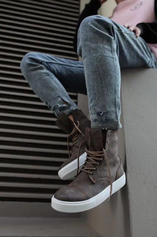 Brown leather combat boots with white platform soles paired with light blue jeans.