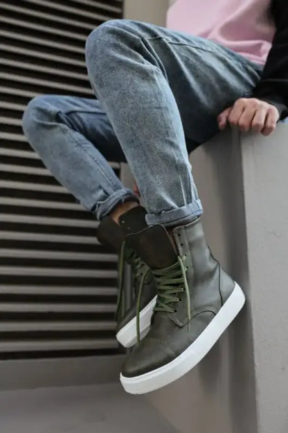 Olive green high-top sneaker with white sole and rolled-up blue jeans.