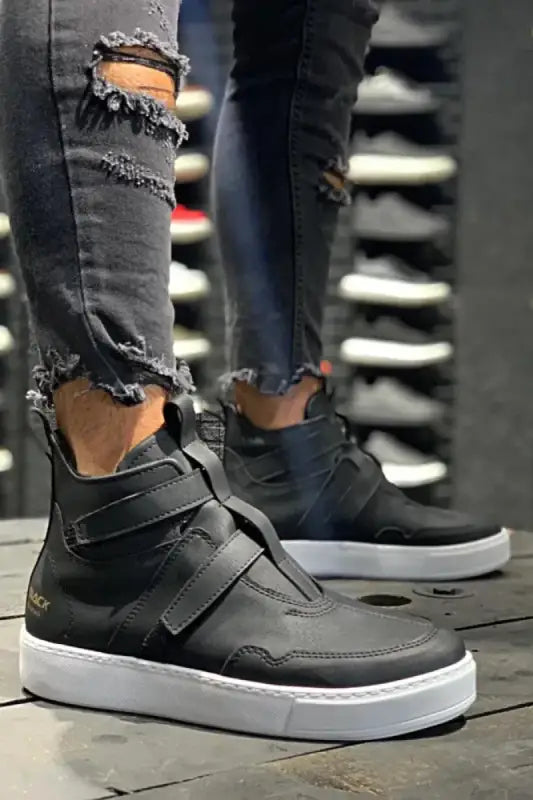 Black high-top sneakers with velcro straps and a white sole.