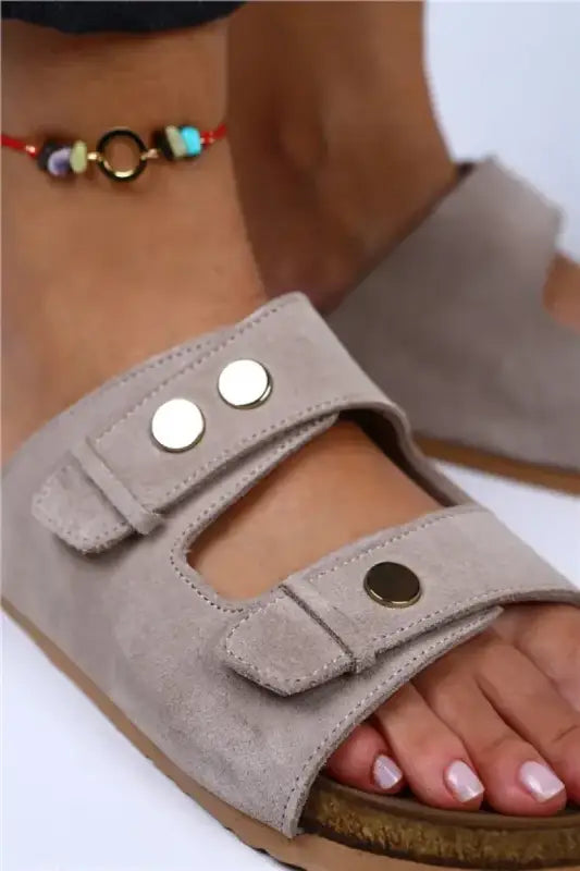 Gray suede sandal with metallic snap buttons and an exposed toe area.