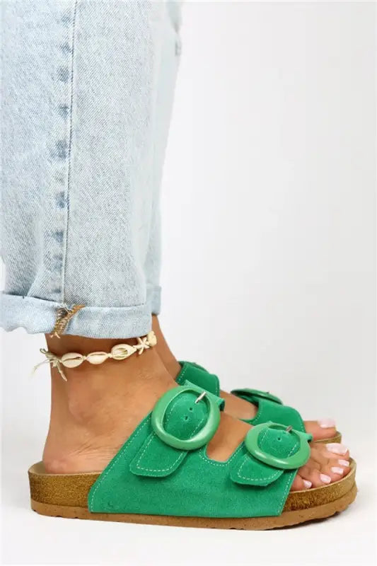 Bright green suede sandals with two buckles and a seashell ankle bracelet.