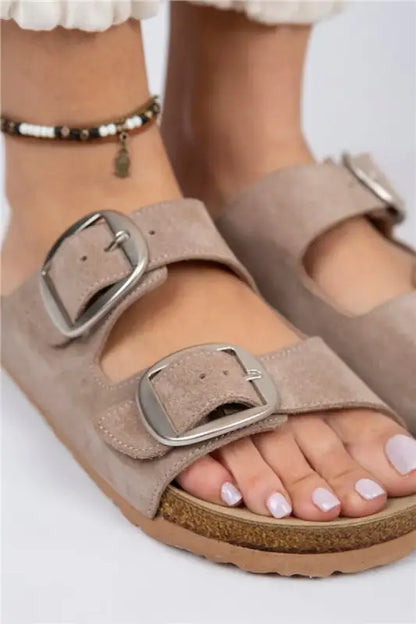 Beige suede sandal with silver buckles and a cork footbed.