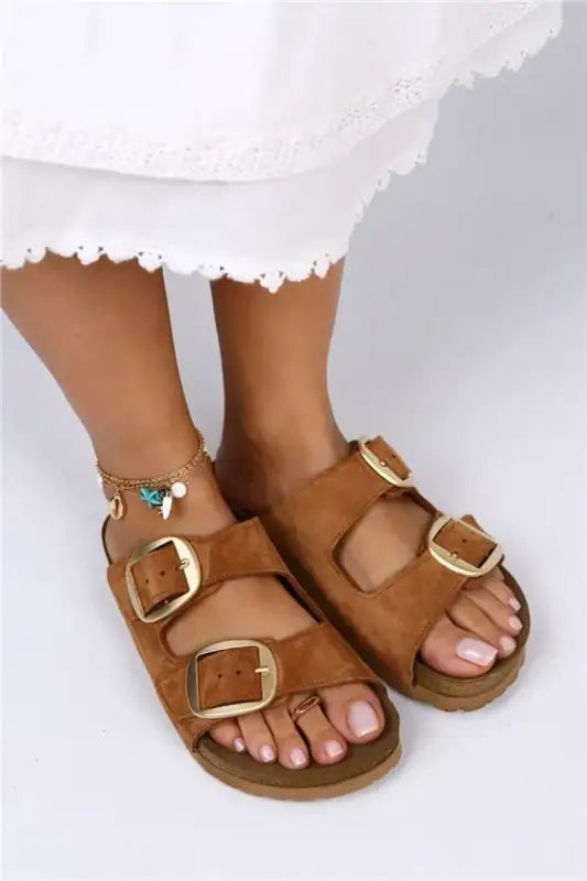 Brown leather sandals with gold buckles and a cork-style footbed.