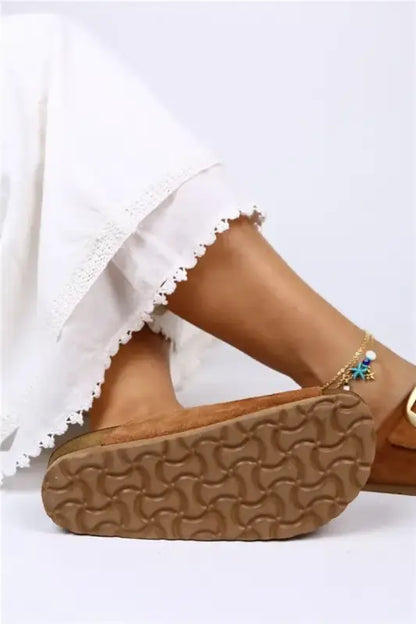 Brown sandal with white daisy trim along the edge and a textured sole.