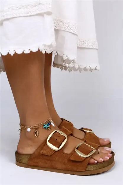 Brown leather sandal with two buckle straps and a turquoise anklet.