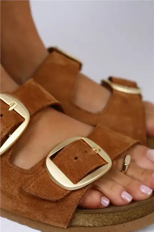 Brown suede sandal with gold buckles and a cork-style sole.