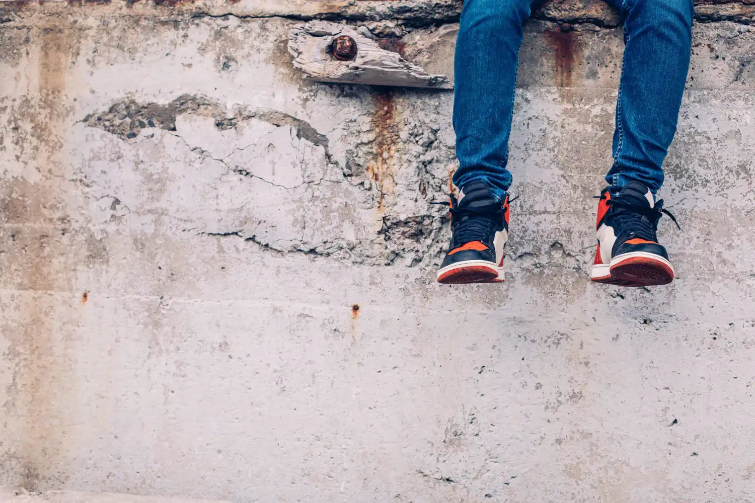 Sneakers with red and black accents paired with blue jeans.