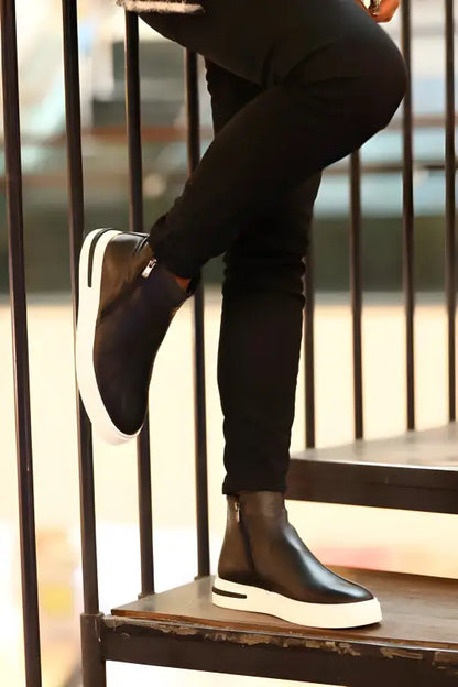 Black and white slip-on sneakers worn with dark pants.