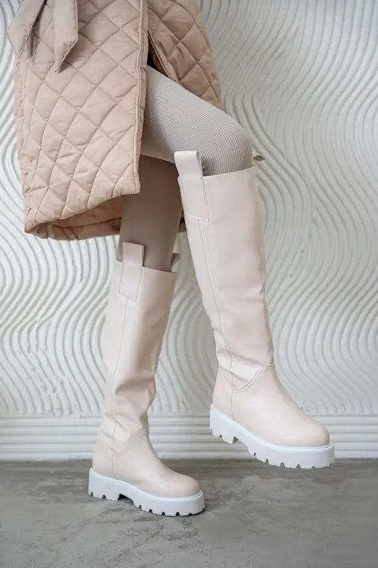 Cream-colored knee-high platform boots with chunky treaded soles.