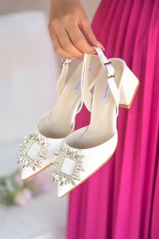 Elegant white slingback heels with crystal embellishments on the pointed toe.