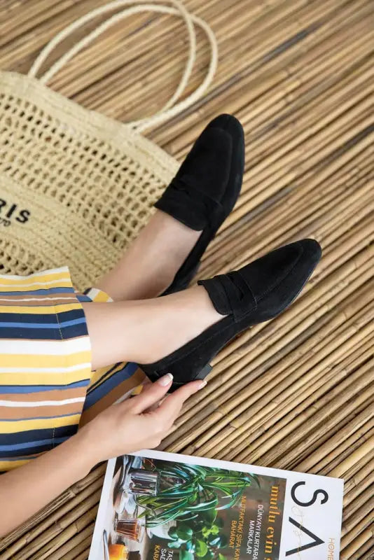 Black suede loafers worn with striped clothing.