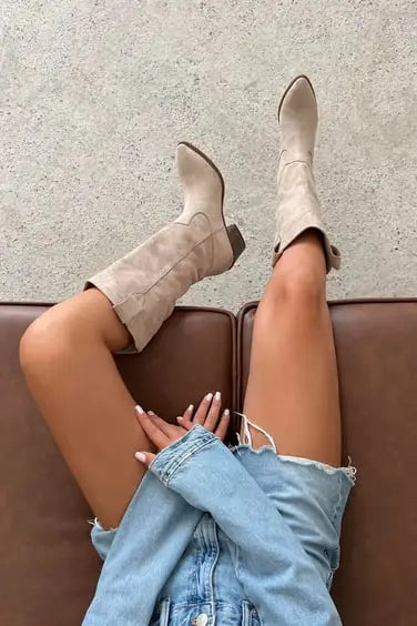 Beige suede ankle boots paired with distressed light-wash denim shorts.