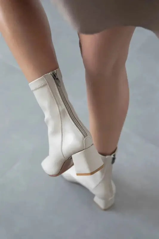 White leather ankle boots with side zippers and a curved heel design.