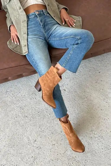 Tan suede ankle boots with a chunky heel paired with light-wash denim jeans.