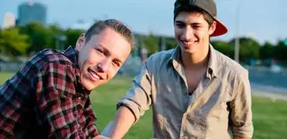 Two friends sharing a lighthearted moment outdoors while wearing casual attire.